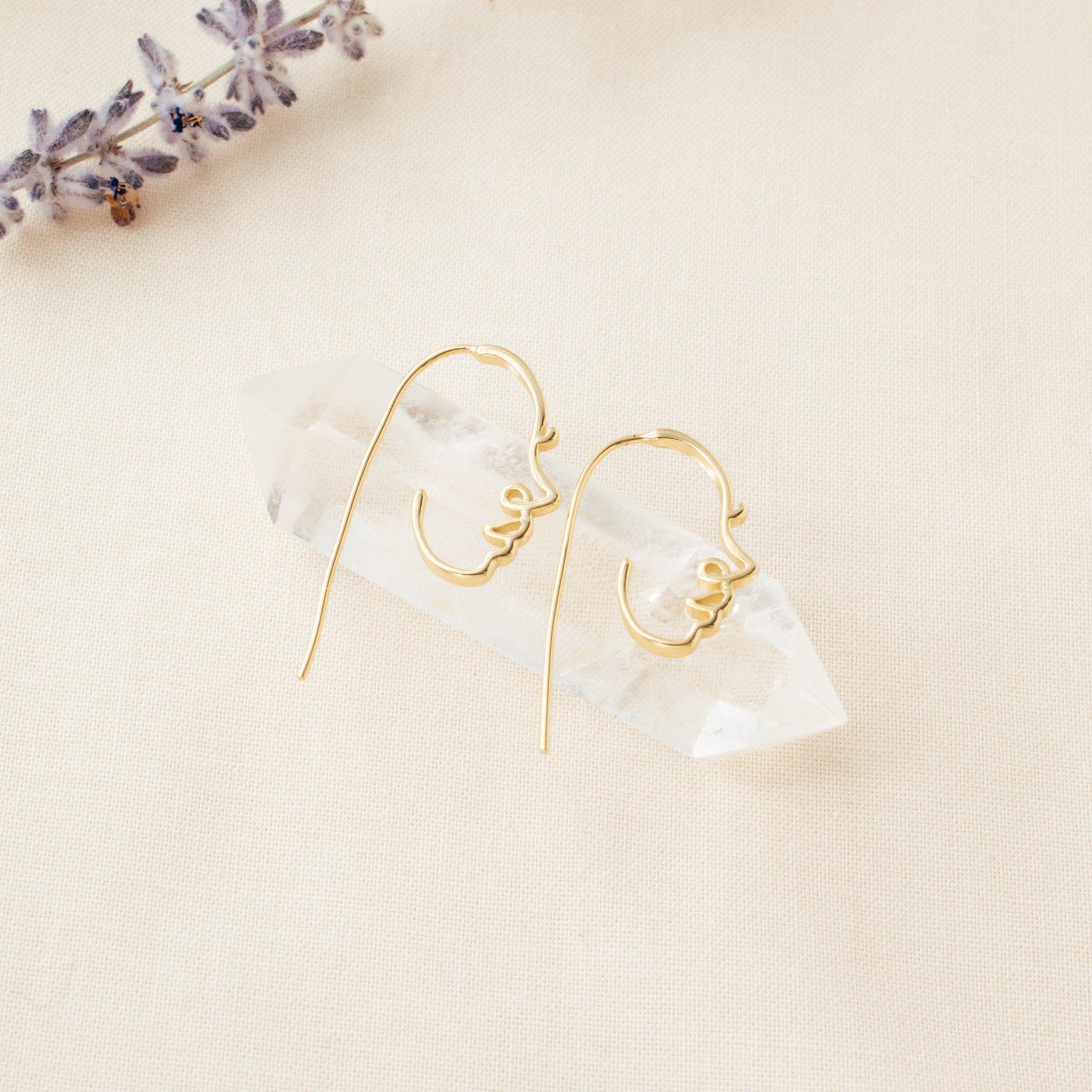 Face earrings on a clear crystal on a cream background