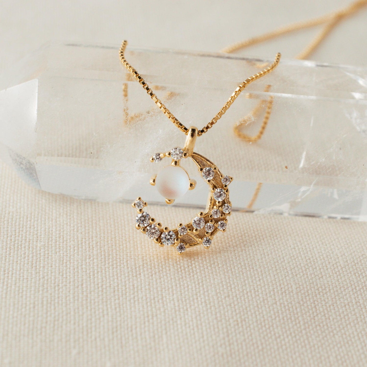 Sparkling Moon Necklace laying on a clear crystal
