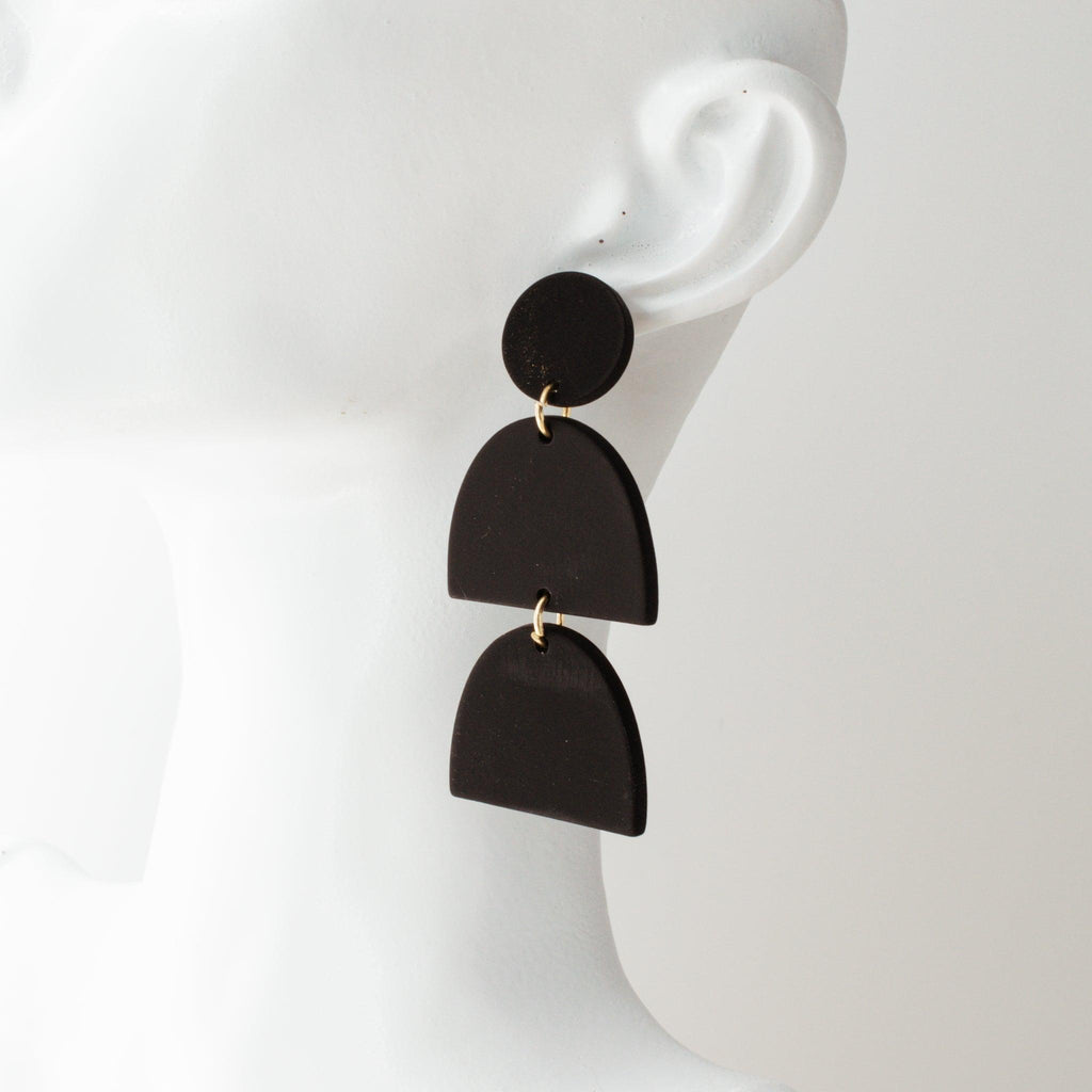 Black polymer clay drop earrings by Avante Jewel laying on a white background