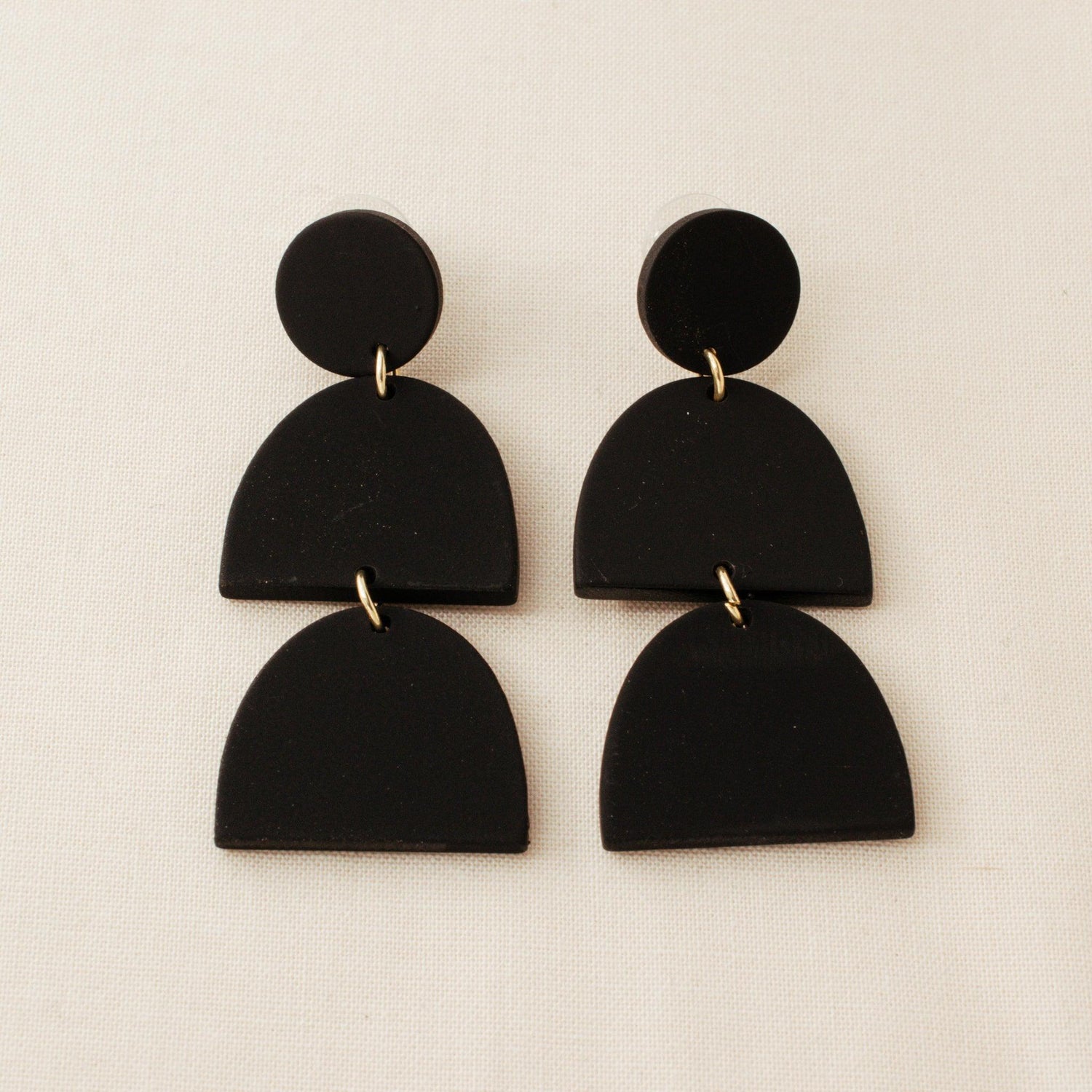 Black polymer clay drop earrings on a cream background