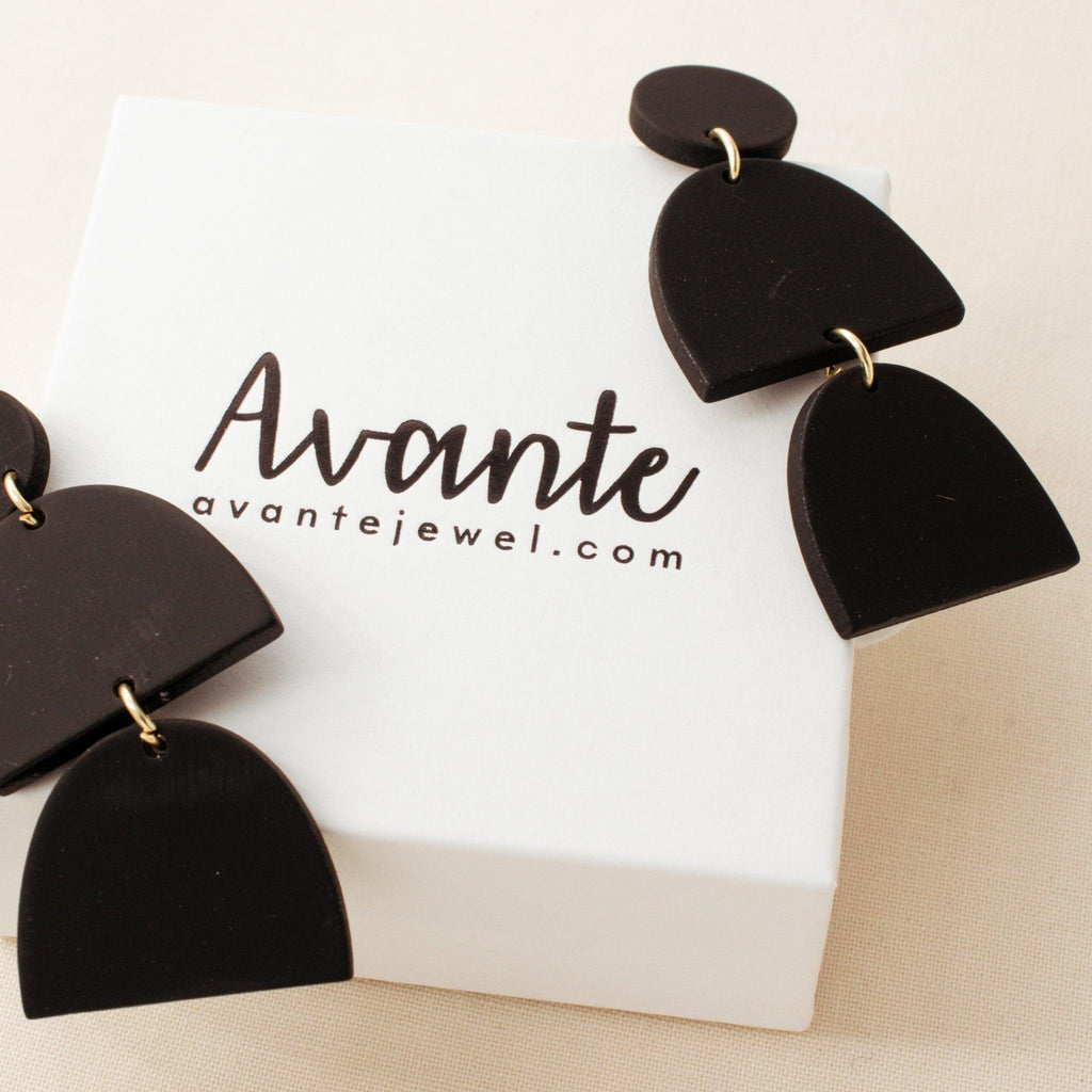 Black polymer clay drop earrings by Avante Jewelry on a gift box