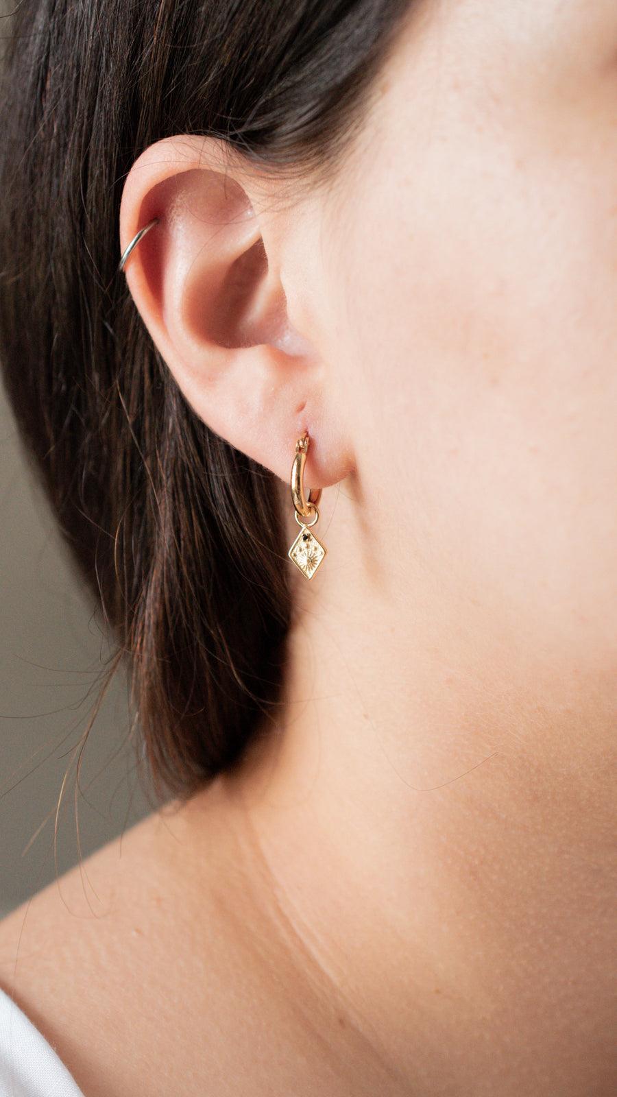 dainty sun earrings showing on model