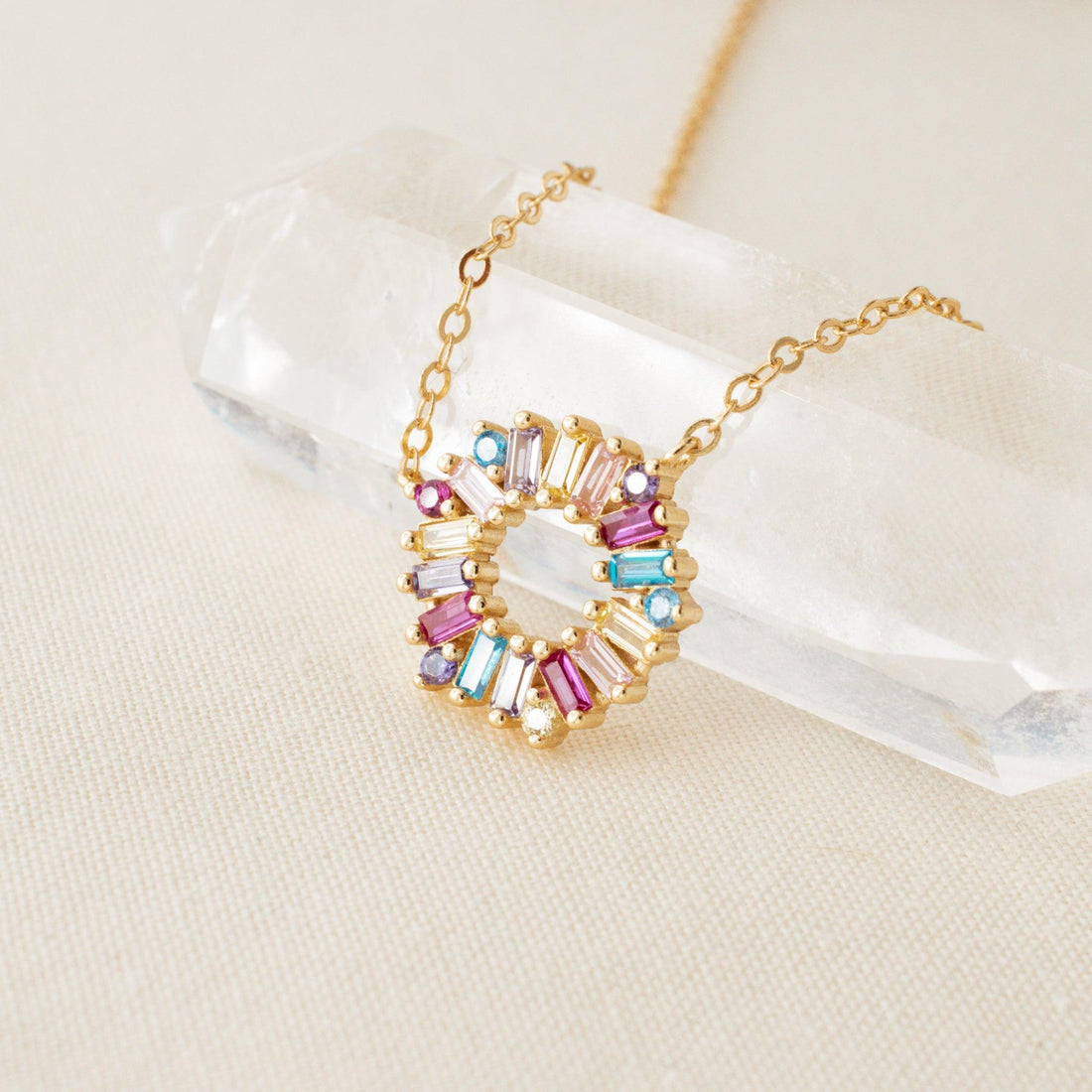 Multicolor Crystal Pendant Necklace by Avante Jewel laying on a clear crystal